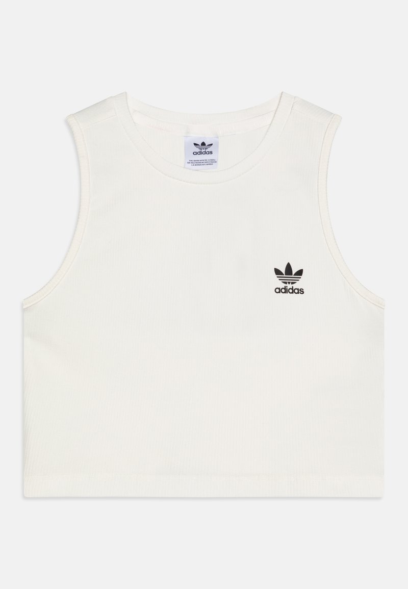 Valkoinen puuvillainen hihaton paita, jossa on ribbikuviointi. Vasemmalla puolella musta Adidas-logo ja pyöreä kaula-aukko. Lyhyt malli.