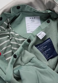 Groene fleece-voering binnenkant met mesh voering, gestreept patroon, labels en hardware. Kenmerken zijn waterdichte stof en geïsoleerde padding.