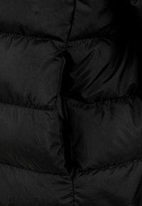 Sort pufferjakke detalje med en quiltet tekstur, polstrede sektioner og glat stof, der viser et rent, minimalistisk design.