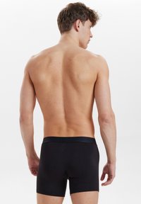 Mustat bokserit, jotka on valmistettu sileästä kankaasta. Ominaisuuksiin kuuluu mukava joustava vyötärönauha ja tiukka istuvuus, yksinkertainen muotoilu.