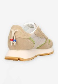Beige suède sneakers met witte textieloverlay, groene zigzagaccenten en een rubberen gumzool. Beschikt over decoratieve veters met rode en blauwe kralen.