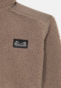 Brown textured fleece jacket with a black Didriksons logo patch and a smooth fabric yoke on the shoulder.