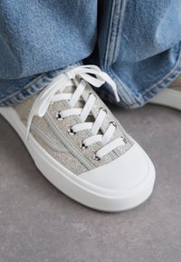Sølvteksturert sneakers med hvit gummisåle, med snøring og sølvfargede øyer, kombinert med lys blå denim.