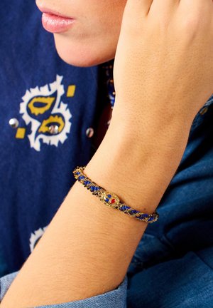 Bracelet featuring a woven design in blue and black threads with a gold closure adorned with colorful accents (red and blue).