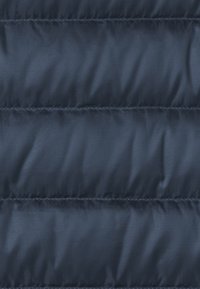 Matériau de doudoune bleu marine avec une texture lisse et brillante, présentant des sections cousues horizontalement et des lignes diagonales subtiles dans le tissu.