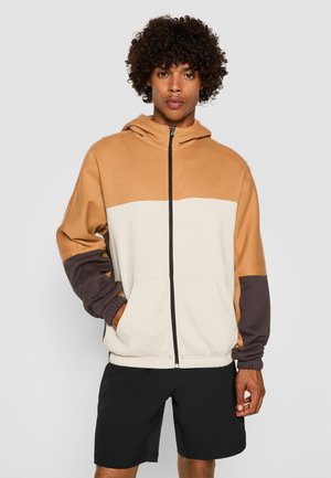Felpa con cappuccio e zip, con colori a blocchi in beige, crema e marrone scuro. Tessuto morbido, tasche a kangaroo, polsini e orlo elasticizzati.