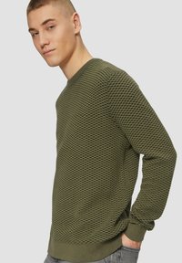 Grüner strukturierter Pullover mit einem Netzmuster, Rundhalsausschnitt und gerippten Bündchen. Besitzt ein tailliertes Design und eine weiche Stoffoberfläche.