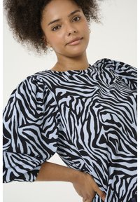 Zebra-gepatroneerde top met een gestructureerde stof, korte pofmouwen en een ronde halslijn in zwart en lichtblauw.