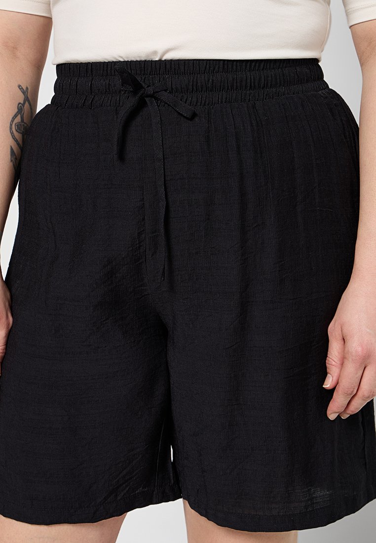 Schwarze Shorts aus strukturiertem Stoff mit einem elastischen Bund und Kordelzug sowie einem lockeren, lässigen Schnitt.