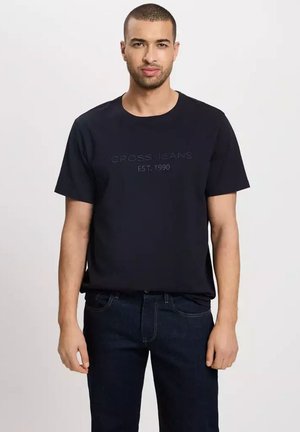 Czarny bawełniany t-shirt z okrągłym dekoltem i krótkimi rękawami. Zawiera wytłoczoną napisem "CROSS JEANS EST. 1990" na wysokości klatki piersiowej.