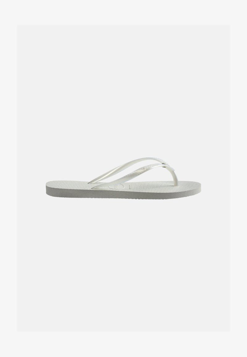 Λευκό καουτσούκ σαγιονάρι με υφή στην σόλα και λεπτά λουράκια σε σχήμα Υ, εμφανιζόμενο από το πλάι σε απλό φωτεινό φόντο.