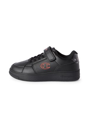 Czarny niski sneaker z sznurowaniem i paskiem na rzep, czerwone logo Champion po boku, teksturowana podeszwa i wyściełany kołnierz z wzorzystym detalem na pięcie.