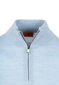 Lichtblauwe trui met een staande kraag, voorzien van een halve rits en textiel met structuur. Zwarte rits hanger met een oranje merketiket aan de binnenkant.