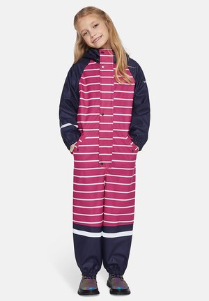 Waternatuurlijk roze en marineblauwe regenpak met witte horizontale strepen, voorzien van een capuchon, drukknoopsluiting en elastische manchetten. Zwarte laarzen maken de outfit compleet.