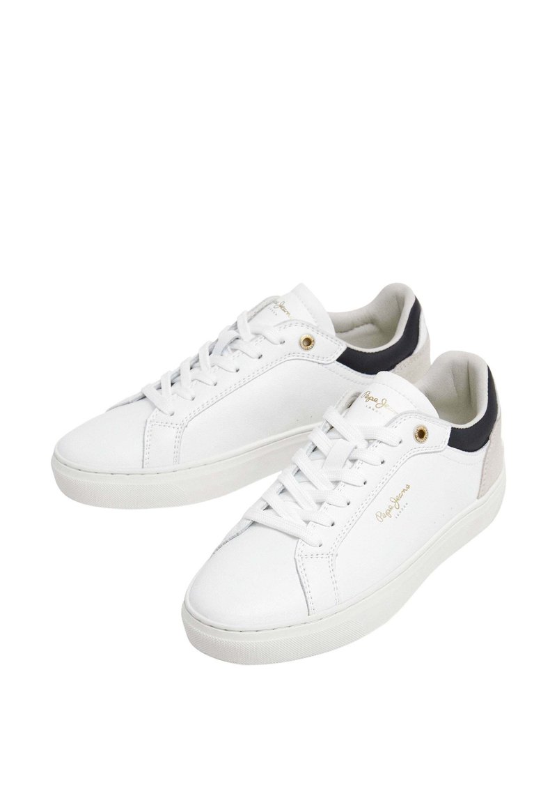 Baskets en cuir blanc avec semelles plates, fermeture à lacets et accents foncés ; présentent un logo doré et des détails de couture.
