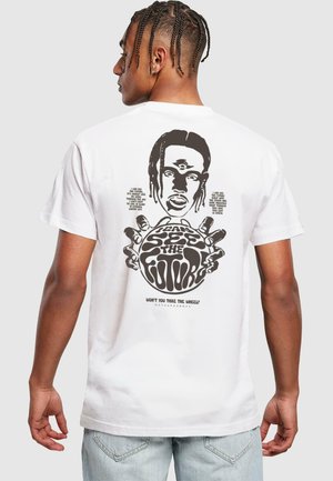 White cotton t-shirt featuring a graphic print on the back with a face, hands, and text in black. Loose fit, short sleeves.