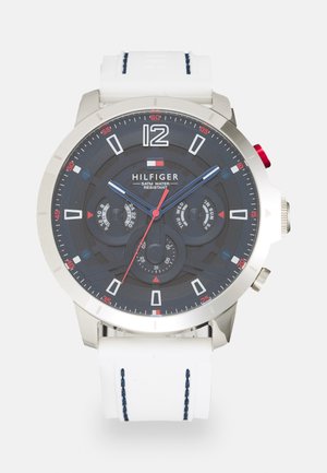 Montre pour homme en tone argenté avec un cadran sombre, un bracelet en silicone blanc et des accents rouges. Comprend les fonctions date, affichage du jour et chronomètre.