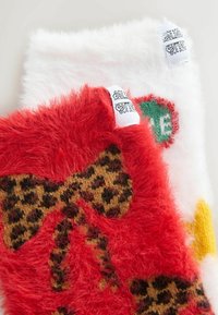 Faux fur-stof i rød og hvid med dyreprint-design. Har mærker med dekorative mønstre. Tekstur og farverige accenter er bemærkelsesværdige.