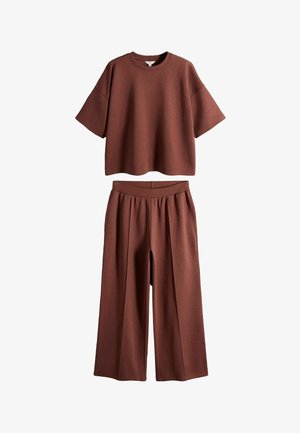 Pruun lühikeste varrukatega lahtine särk, mis on kombineeritud kõrge vöökohaga, laiade jalgadega pükstega sama kanga ja värviga.