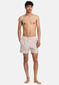Simshorts i ljus beige med blommönster, elastiskt midjeband, dragsko och sidofickor. Slät, lättviktsmaterial.