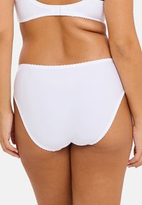Shorty taille haute blanche en tissu lisse avec des bords festonnés. Présente un design offrant une couverture arrière complète pour un confort et un soutien maximaux.