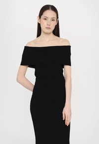 Black off-the-shoulder dress made of smooth fabric, fitted silhouette, and knee-length hem highlighting the body's shape and contours.
