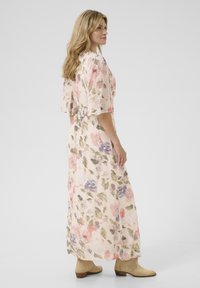 Rochie maxi floral dintr-un material moale și ușor, cu nuanțe pastelate. Are mâneci scurte, o talie strânsă și o siluetă lejeră și fluidă.