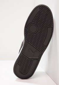 Schwarze Gummisohle mit strukturiertem Zickzackmuster und kreisförmigen Details. Verfügt über ein Logo in der Nähe der Ferse. Elegantes und flaches Design.