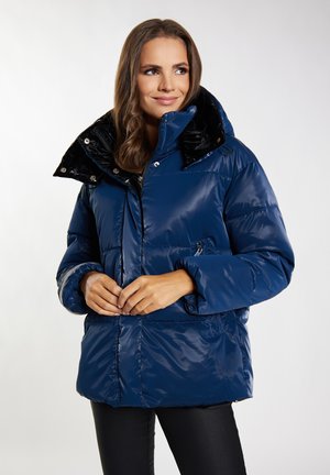 Mørkeblå puffjakke med en blank finish, høj krave og sort indvendigt. Har en frontzipper og sidelommer. Blød tekstur.