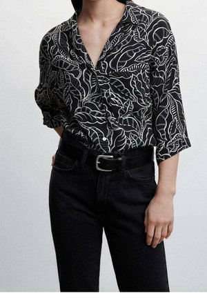 Black blouse with white leaf pattern, button-down front, and 3/4 sleeves. Worn with high-waisted black jeans and a black belt.