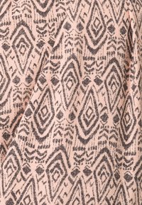 Růžová látka s geometrickým vzorem v černé barvě, se špičatými tvary a dalšími liniovými designy, vytvářející texturovaný vzhled.