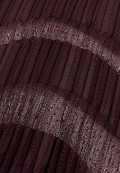Tela plisada de color burdeos profundo con bandas horizontales de malla transparente que presentan delicados patrones de puntos.