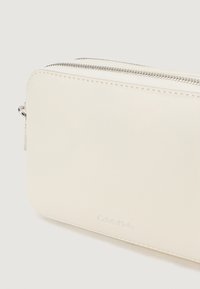 Hvid læder clutch med sølv lynlås, glat tekstur, afrundede kanter og præget logo. Minimalistisk design uden yderligere udsmykninger.