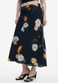 Svævende sort nederdel med gul og hvid marguerit-blomster mønster, lavet af letvægtsstof. Har en sidelæg og en glat tekstur.