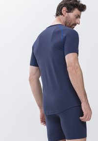 Marineblauw sport T-shirt met korte mouwen, met contrasterende blauwe stitching. Fitted ontwerp, gecombineerd met bijpassende shorts. Ruwe textuur.