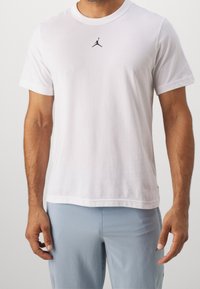 Vit bomullströja med rundhals och korta ärmar, med en liten svart Jumpman-logga på bröstet, som har en normal passform och mjuk textur.