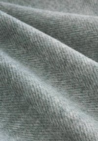 Soft light gray fabric with a subtle textured pattern and gentle folds creating a smooth, wavy surface.