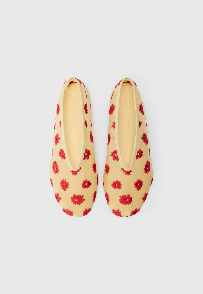Pantofole gialle con ricami di fiori rossi, punta arrotondata, suola piatta e apertura elasticizzata per una facile vestibilità. Materiale in tessuto morbido.