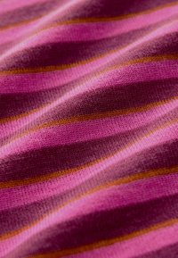 Gros plan d'un tissu tricoté rose et violet avec de fines rayures horizontales orange et rose clair et une texture visible.