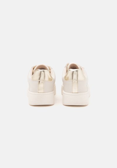 Ζευγάρι λευκά πλατφόρμα sneakers με μεταλλικά χρυσά σημεία στη φτέρνα, εμφανισμένα από πίσω σε απλό ανοιχτό φόντο.
