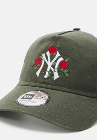 Olivgrüne verstellbare Kappe mit gesticktem weißen NY-Logo, umgeben von roten Rosen und grünen Blättern, mit strukturiertem Schirm und Logosticker.