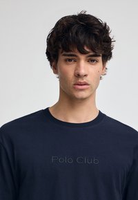 Sudadera azul marino con cuello redondo, mangas largas y lettering texturizado "Polo Club" en el pecho. Tejido suave con un acabado liso.