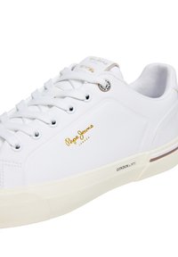 Λευκά αθλητικά παπούτσια με λείο φινίρισμα, σχεδιασμό με κορδόνια, χρυσό λογότυπο και υφή στην σόλα· διαθέτουν διακριτική επωνυμία και μινιμαλιστική κατασκευή.