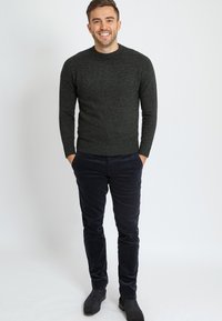 Dunkelgrauer Strickpullover mit Rundhalsausschnitt, kombiniert mit marineblauen Cordhosen. Das Outfit zeichnet sich durch gerippte Bündchen und eine taillierte Passform aus.