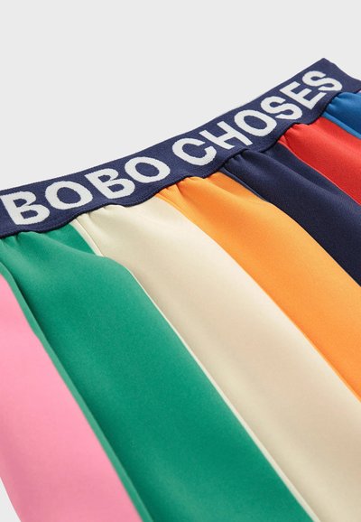 Elastyczny pas z tekstem "BOBO CHOSES" na materiałach w paski w kolorach różowym, zielonym, kremowym, pomarańczowym, granatowym, czerwonym i niebieskim.
