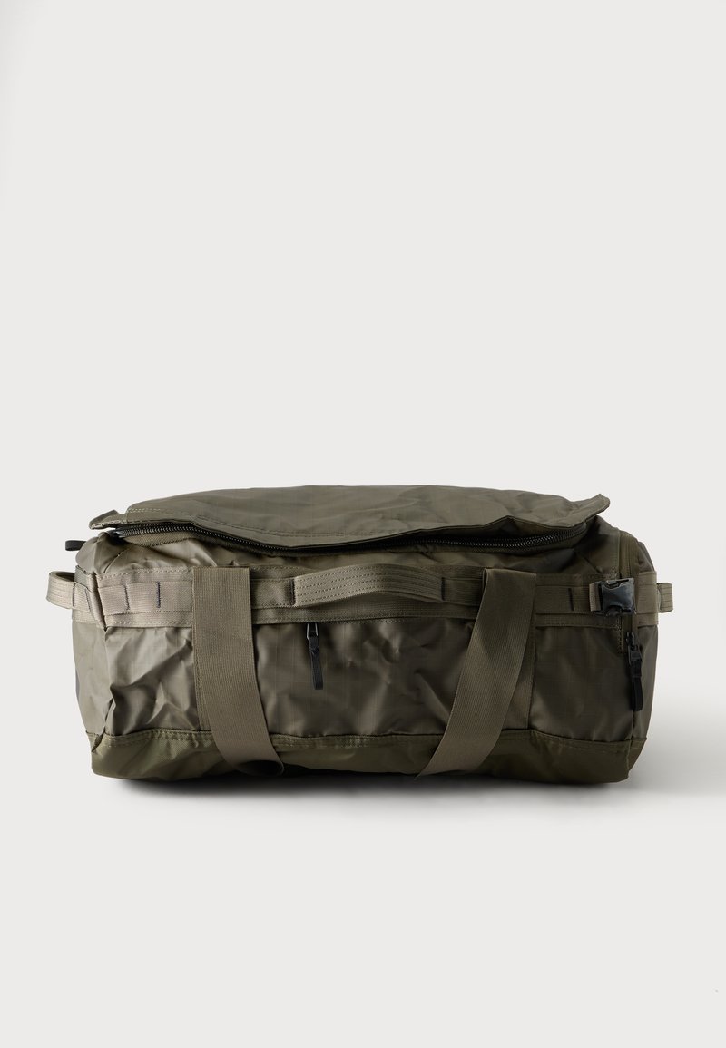 Τσάντα duffel σε ελιόχρωμο με διπλές λαβές και μερικώς ανοιχτό φερμουάρ στην κορυφή, σε απλό ανοιχτό φόντο.