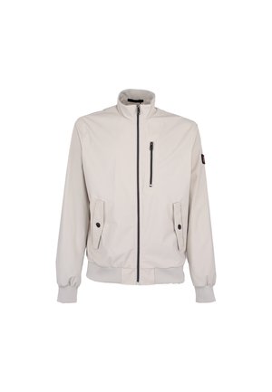 Licht beige jas met rits en opstaande kraag, twee klepzakken met knoop, één verticale borstzak met rits, en geribde manchetten en zoom.