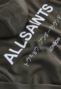 Hoodie gris à finition texturée, avec des lettres blanches audacieuses "ALLSAINTS" et "LONDRES" sur le devant, comprenant des caractères japonais.