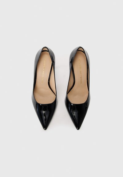 Escarpins en cuir verni noir avec un bout pointu, finition lisse et design avec découpes sur les côtés. Présentent une semelle intérieure en cuir nude et un logo.