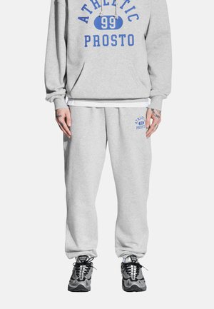 Szara bluza z kapturem z niebieskim napisem, w połączeniu z szarymi dresami z niebieskimi akcentami. Obie części wykonane są z miękkiego, komfortowego materiału. Czarne sneakersy dopełniają stylizację.